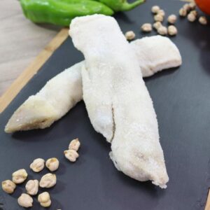 Dos pies de cerdo salados, sobre una tabla con decoración de pimientos y garbanzos