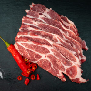 Cebecero de cerdo Duroc fileteado sobre una tabla, con adorno de guindilla roja