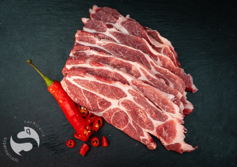 Cebecero de cerdo Duroc fileteado sobre una tabla, con adorno de guindilla roja
