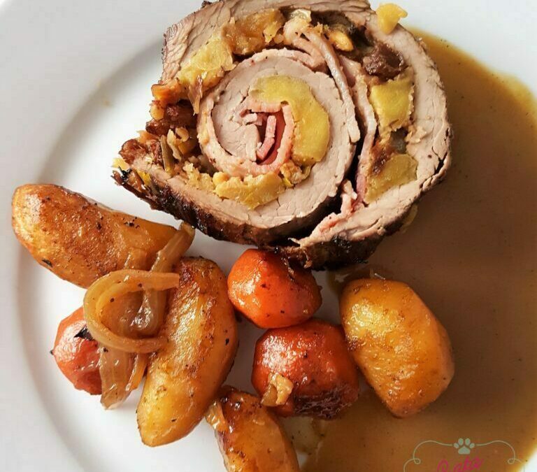 Un plato con una porción de aleta de ternera rellena, con guarnición de manzana y pasas