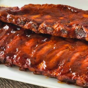 Un plato con dos tiras de costillas de cerdo con abundante salsa barbacoa