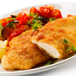 Un plato de pechugas de pollo empanadas con guarnición de ensalada