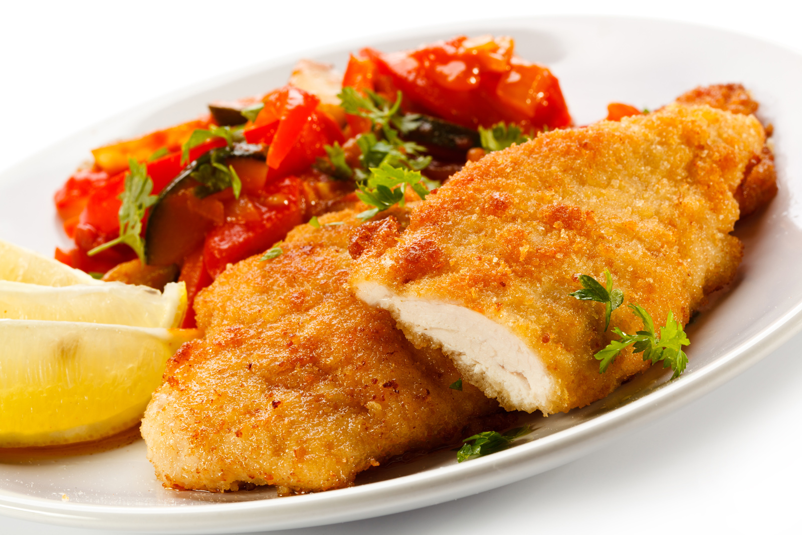 Un plato de pechugas de pollo empanadas con guarnición de ensalada